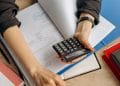 Person Holding Black Calculator While Using Laptop